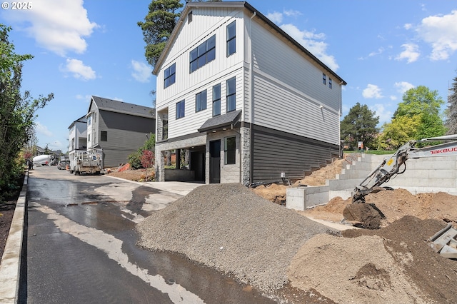 contemporary home featuring a carport, board and batten siding, and aphalt driveway