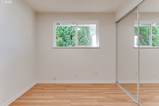331 Limerick Ave, Eugene, OR 97404 - unfurnished bedroom with a closet, light wood-style floors, multiple windows, and a textured ceiling