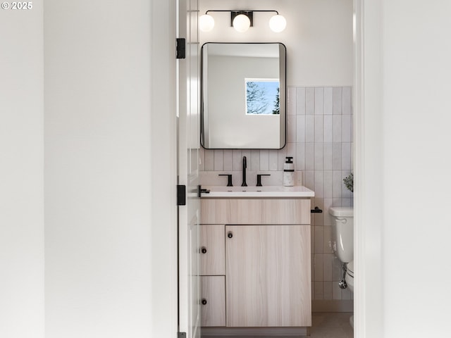 bathroom with tile walls, toilet, and vanity