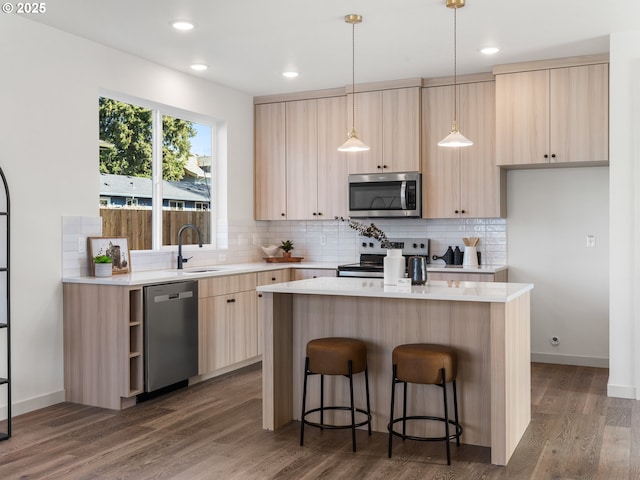 kitchen with appliances with stainless steel finishes, light countertops, light brown cabinets, and a kitchen bar