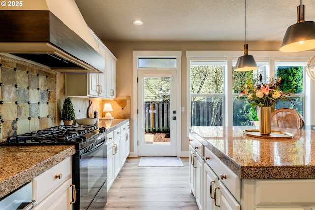 kitchen featuring light hardwood / wood-style flooring, black gas stove, custom range hood, decorative backsplash, and white cabinets