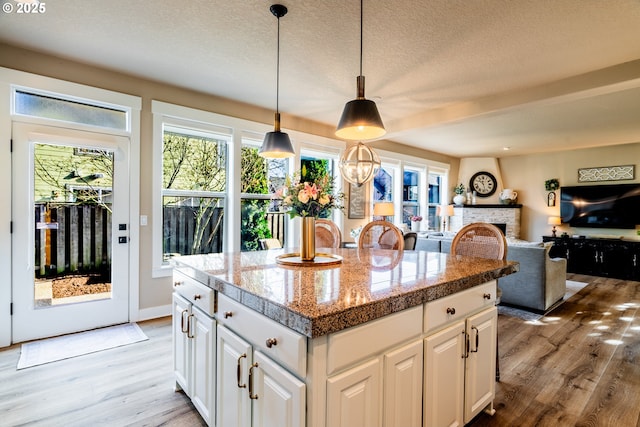 kitchen with white cabinetry, decorative light fixtures, light hardwood / wood-style flooring, and a kitchen island