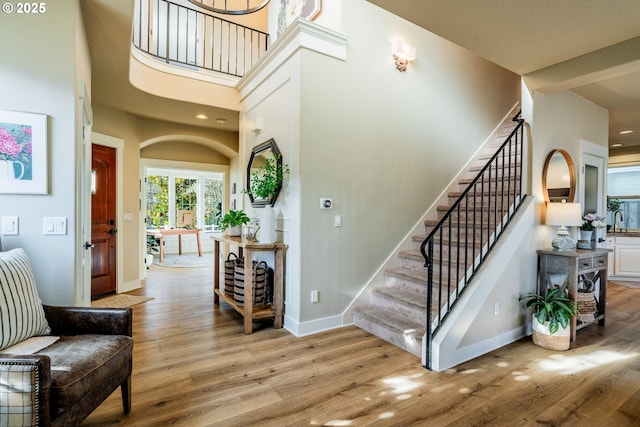 staircase with hardwood / wood-style floors and a towering ceiling