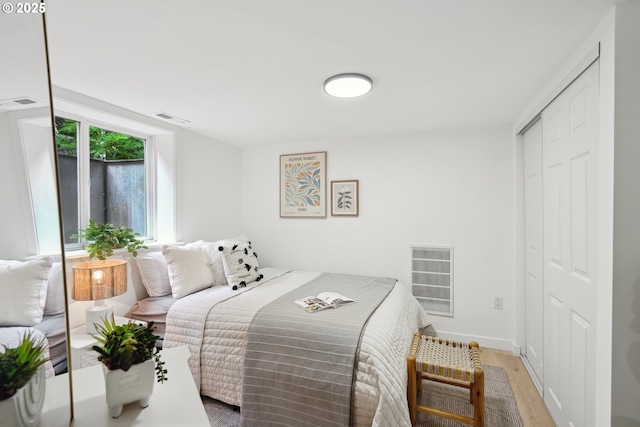 bedroom with wood finished floors, a closet, and baseboards