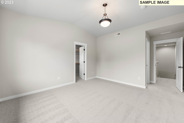 spare room featuring lofted ceiling, baseboards, visible vents, and light colored carpet