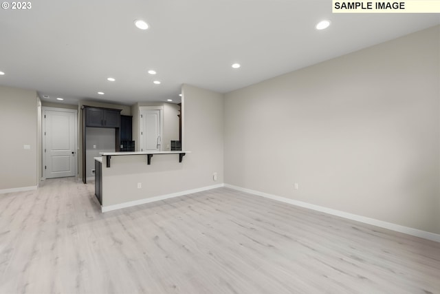 kitchen with light wood-style floors, baseboards, a breakfast bar, and recessed lighting