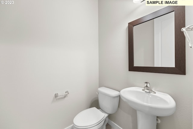 bathroom with toilet, baseboards, and a sink