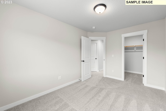 unfurnished bedroom featuring a closet, baseboards, a walk in closet, and carpet flooring