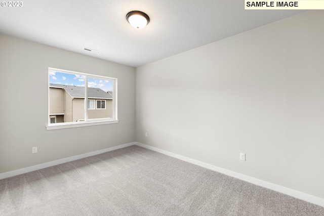 carpeted spare room with visible vents and baseboards