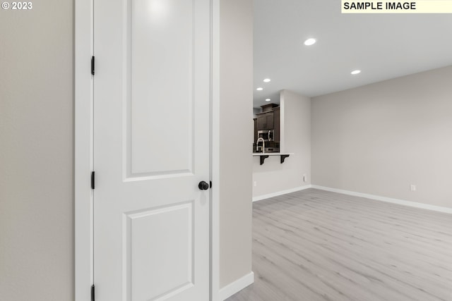 hall with recessed lighting, baseboards, and light wood finished floors