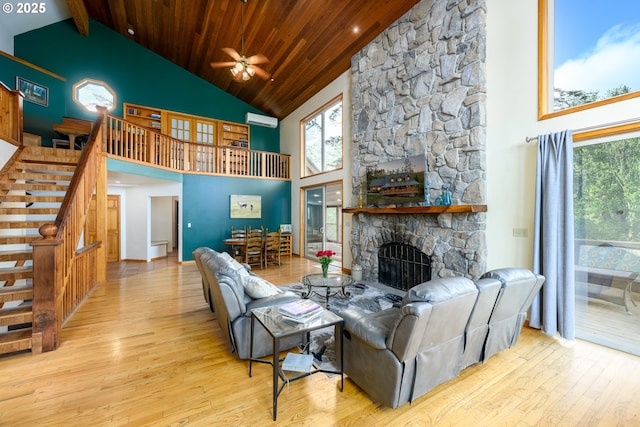 living room featuring a stone fireplace, wood ceiling, high vaulted ceiling, light hardwood / wood-style flooring, and an AC wall unit