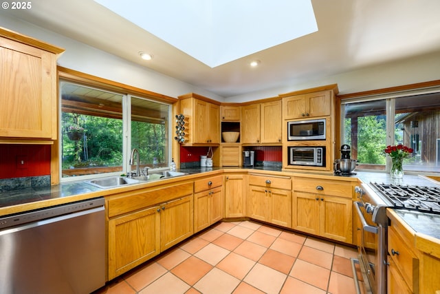 kitchen featuring sink, light tile patterned floors, a skylight, stainless steel appliances, and tile countertops