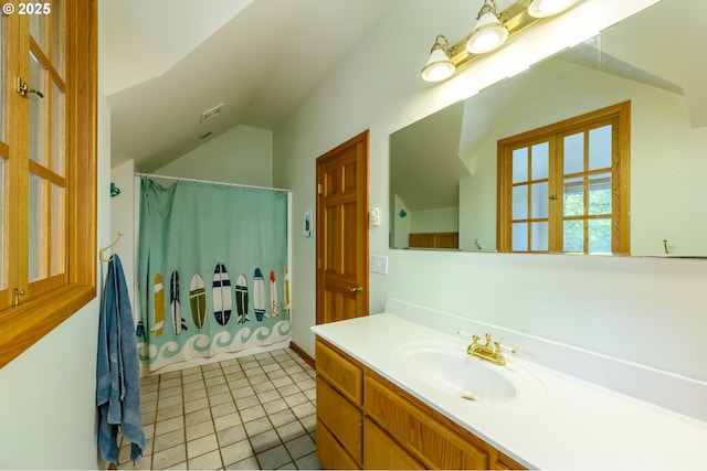 bathroom featuring vanity, tile patterned flooring, vaulted ceiling, and walk in shower