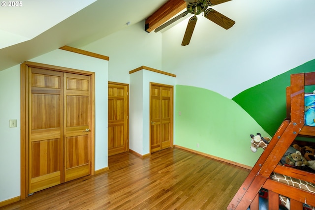 unfurnished bedroom with beam ceiling, wood-type flooring, high vaulted ceiling, and ceiling fan