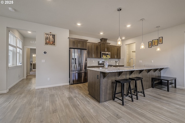 30942 NW Turel Dr, North Plains, OR 97133 - kitchen featuring stainless steel appliances, a sink, a kitchen breakfast bar, a peninsula, and light wood-type flooring