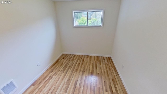 empty room featuring light wood-type flooring, visible vents, and baseboards