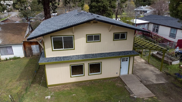 back of house featuring roof with shingles and a yard