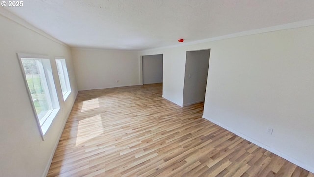 unfurnished room with ornamental molding, light wood-type flooring, and baseboards