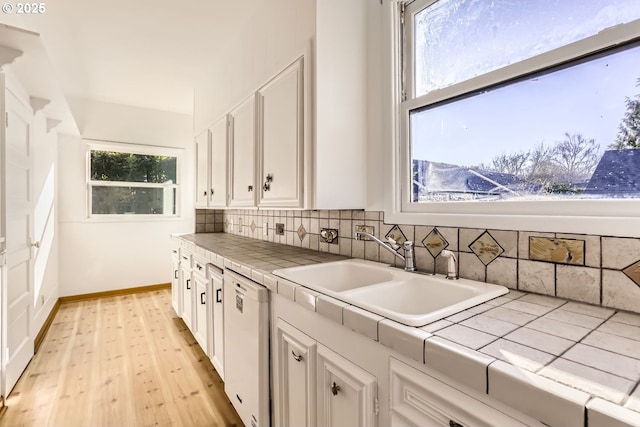 kitchen featuring sink, tasteful backsplash, tile counters, dishwasher, and white cabinets