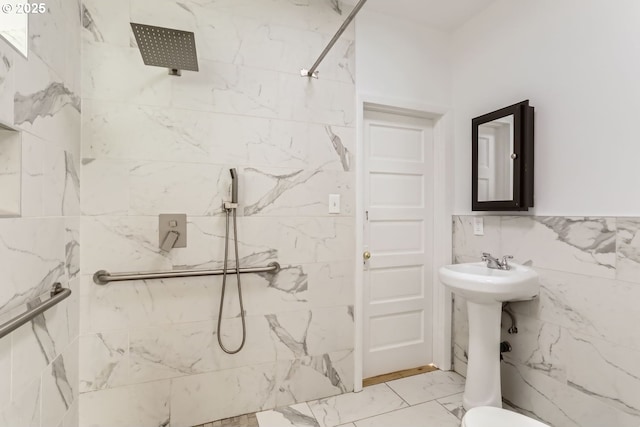 bathroom with a tile shower, sink, and tile walls