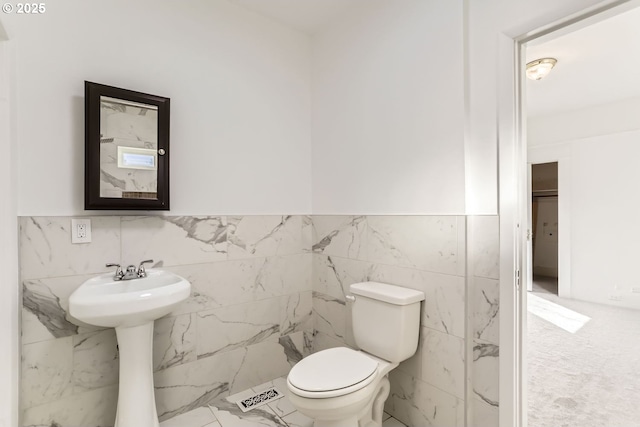 bathroom featuring tile walls and toilet