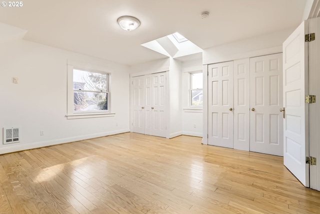 additional living space with light hardwood / wood-style floors and a skylight