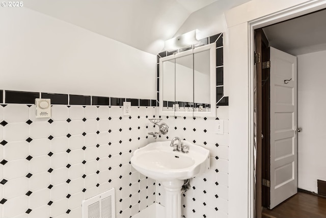 bathroom featuring lofted ceiling and tile walls