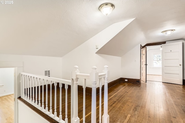 additional living space featuring hardwood / wood-style flooring, lofted ceiling, and a textured ceiling