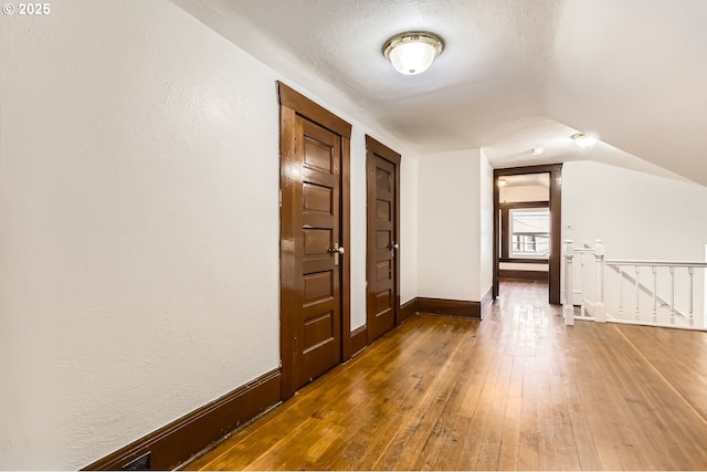 interior space featuring dark hardwood / wood-style flooring, vaulted ceiling, and a textured ceiling