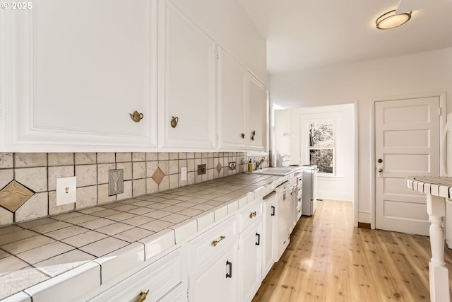 kitchen featuring tasteful backsplash, tile counters, and white cabinets