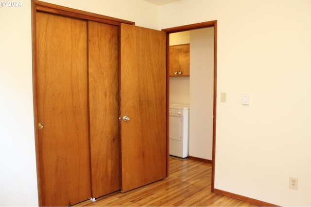 unfurnished bedroom with washer / clothes dryer, light wood-style flooring, a closet, and baseboards