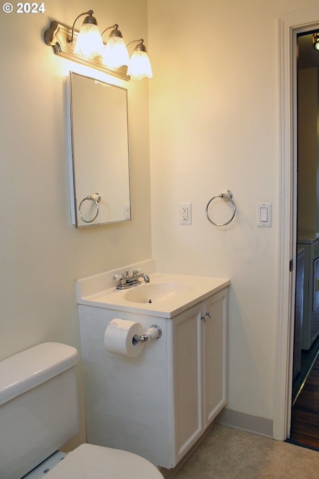 half bathroom with toilet, vanity, and baseboards