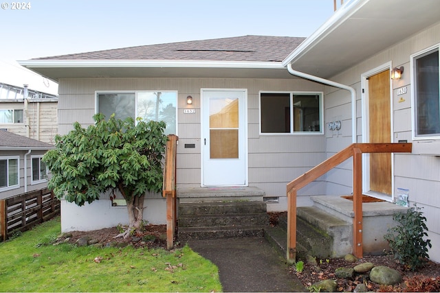 entrance to property featuring roof with shingles
