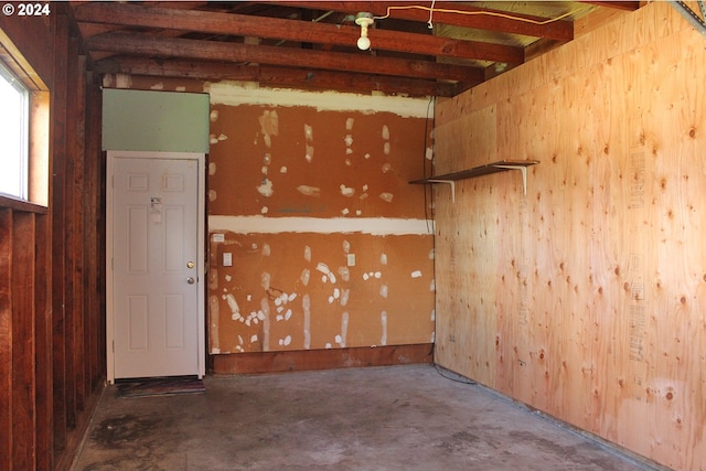 spare room with unfinished concrete flooring and wooden walls
