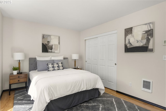 bedroom featuring wood finished floors, a closet, baseboards, and heating unit