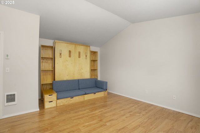 unfurnished room with wood finished floors, lofted ceiling, and baseboards