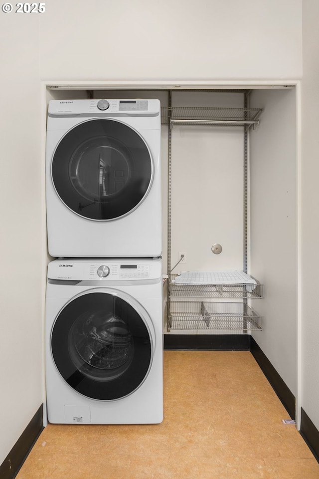 clothes washing area with stacked washer / dryer and baseboards