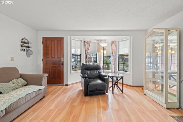 sitting room featuring baseboards, light wood finished floors, and a notable chandelier