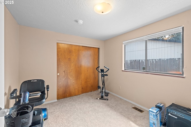 exercise room featuring visible vents, baseboards, carpet floors, and a textured ceiling