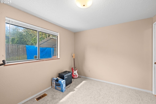 carpeted spare room with a textured ceiling, baseboards, and visible vents
