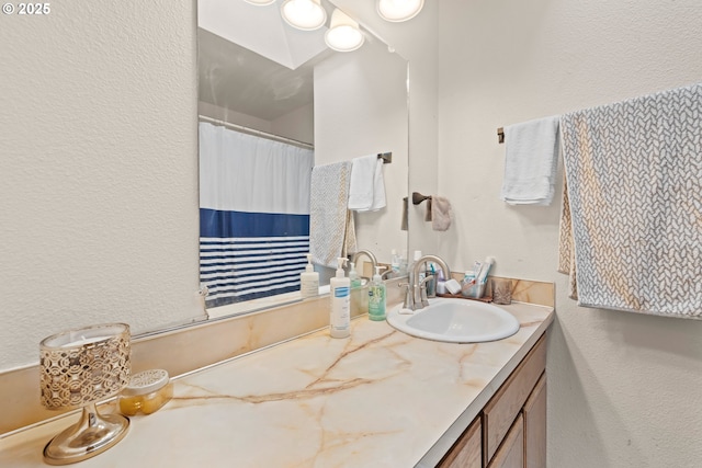 full bathroom with a textured wall, vanity, and a shower with curtain