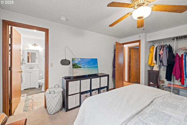 carpeted bedroom featuring a closet, a sink, a ceiling fan, and connected bathroom