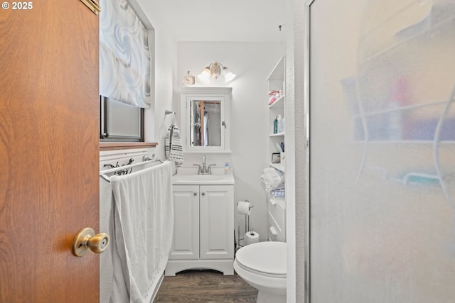 bathroom with toilet, wood finished floors, and vanity