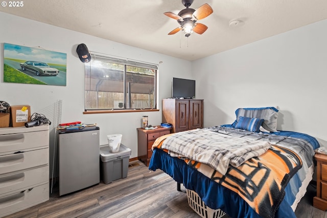 bedroom featuring ceiling fan, freestanding refrigerator, and wood finished floors