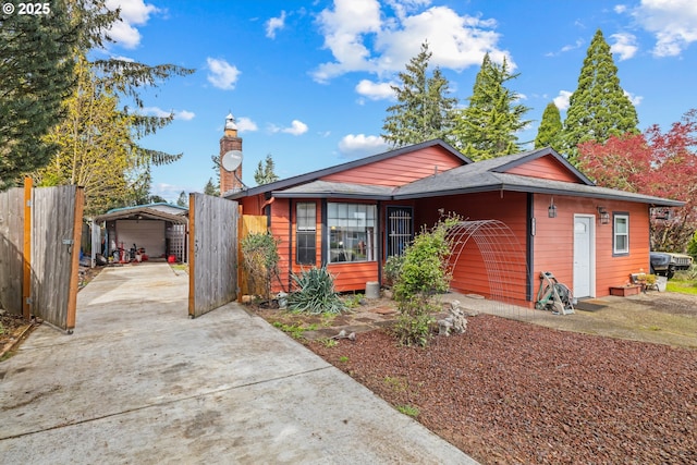 view of front of property with a detached carport, fence, and concrete driveway