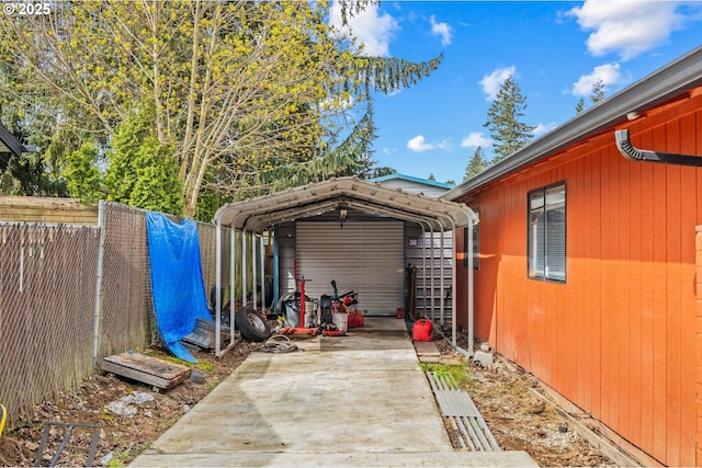 view of patio / terrace featuring concrete driveway, a carport, and a fenced backyard