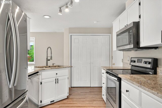 110 Wilshire Way, Kelso, WA 98626 - kitchen with appliances with stainless steel finishes, a sink, white cabinetry, and light wood finished floors