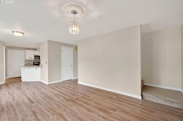 110 Wilshire Way, Kelso, WA 98626 - unfurnished living room featuring baseboards, light wood-style floors, a sink, and a chandelier
