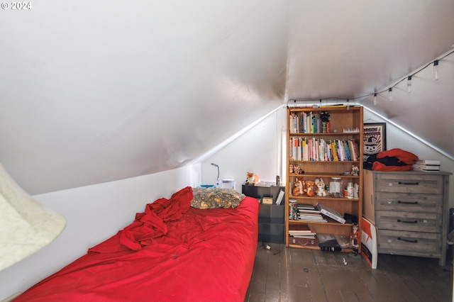 bedroom with vaulted ceiling, rail lighting, and dark wood-type flooring