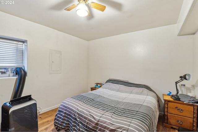 bedroom with ceiling fan, electric panel, and light hardwood / wood-style floors